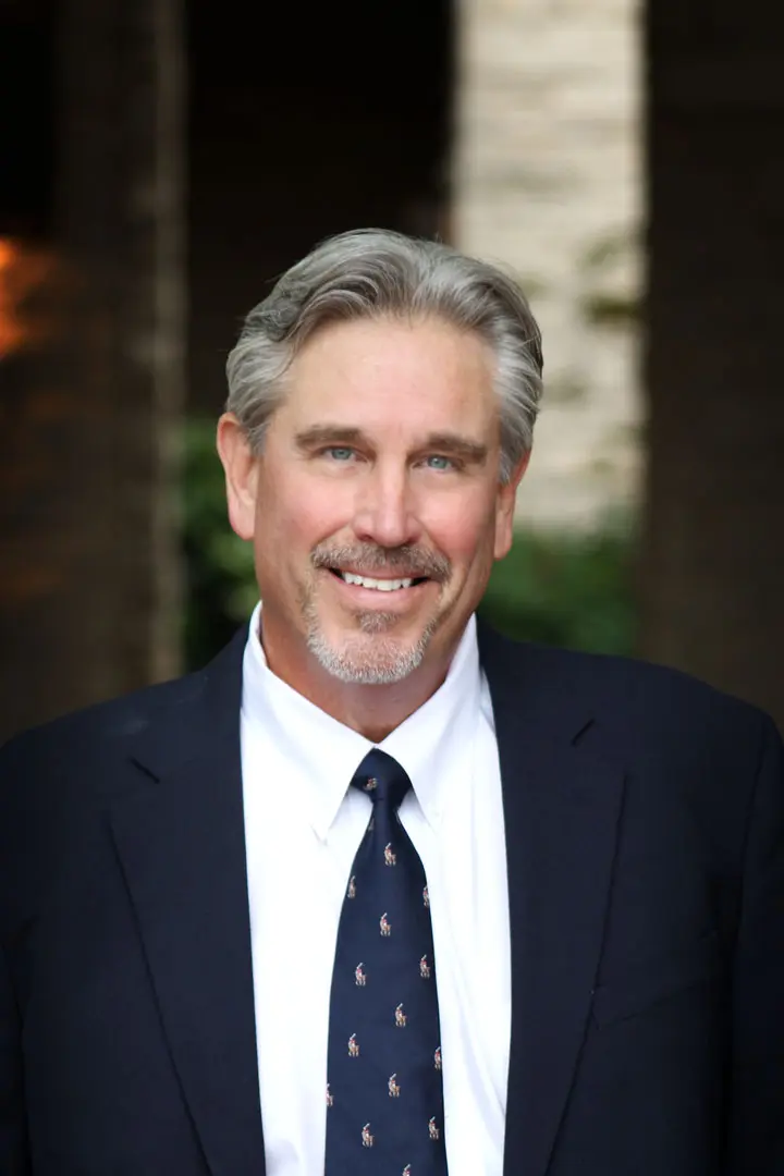 A man in suit and tie smiling for the camera.