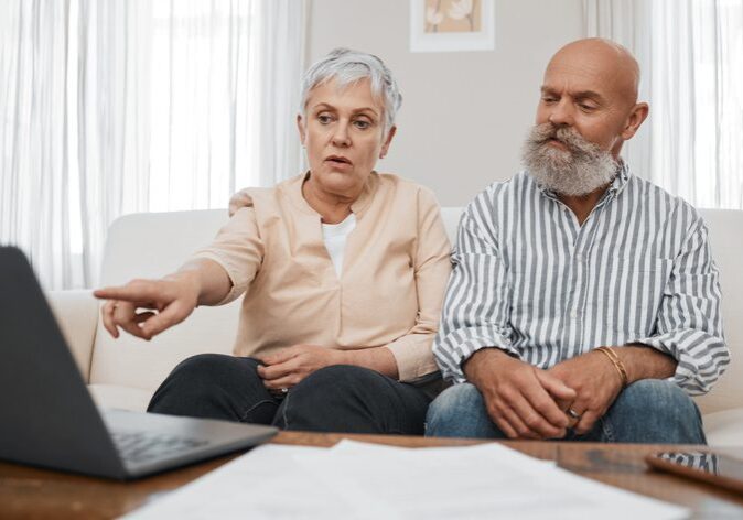 Budget, finance and senior couple with laptop planning financial investments, mortgage or tax papers. Elderly woman apeaking of bills, debt and pension fund on bank statement with an old man at home